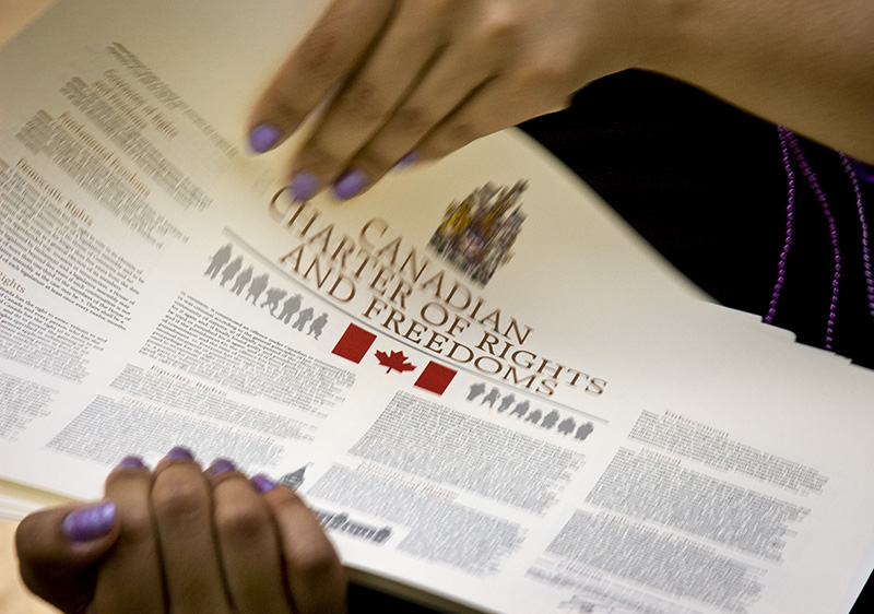 photo of two hands holding a printed copy of the Canadian Charter of Rights And Freedoms
