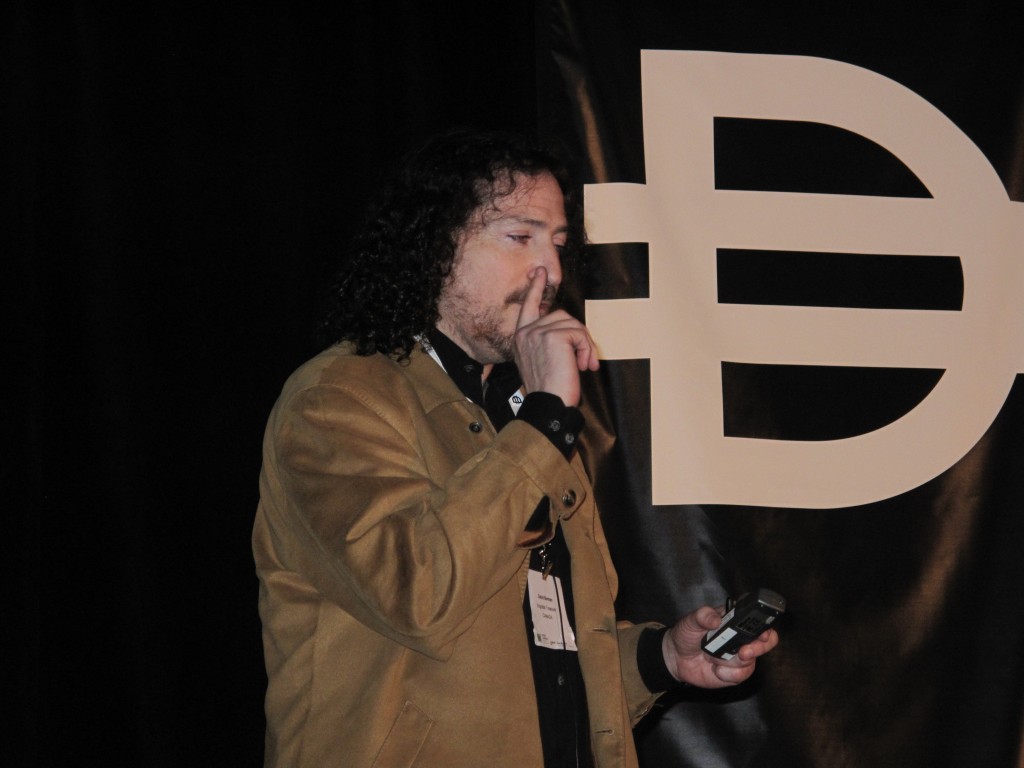 Photo of David Berman on stage, in front of Design Currency branding.