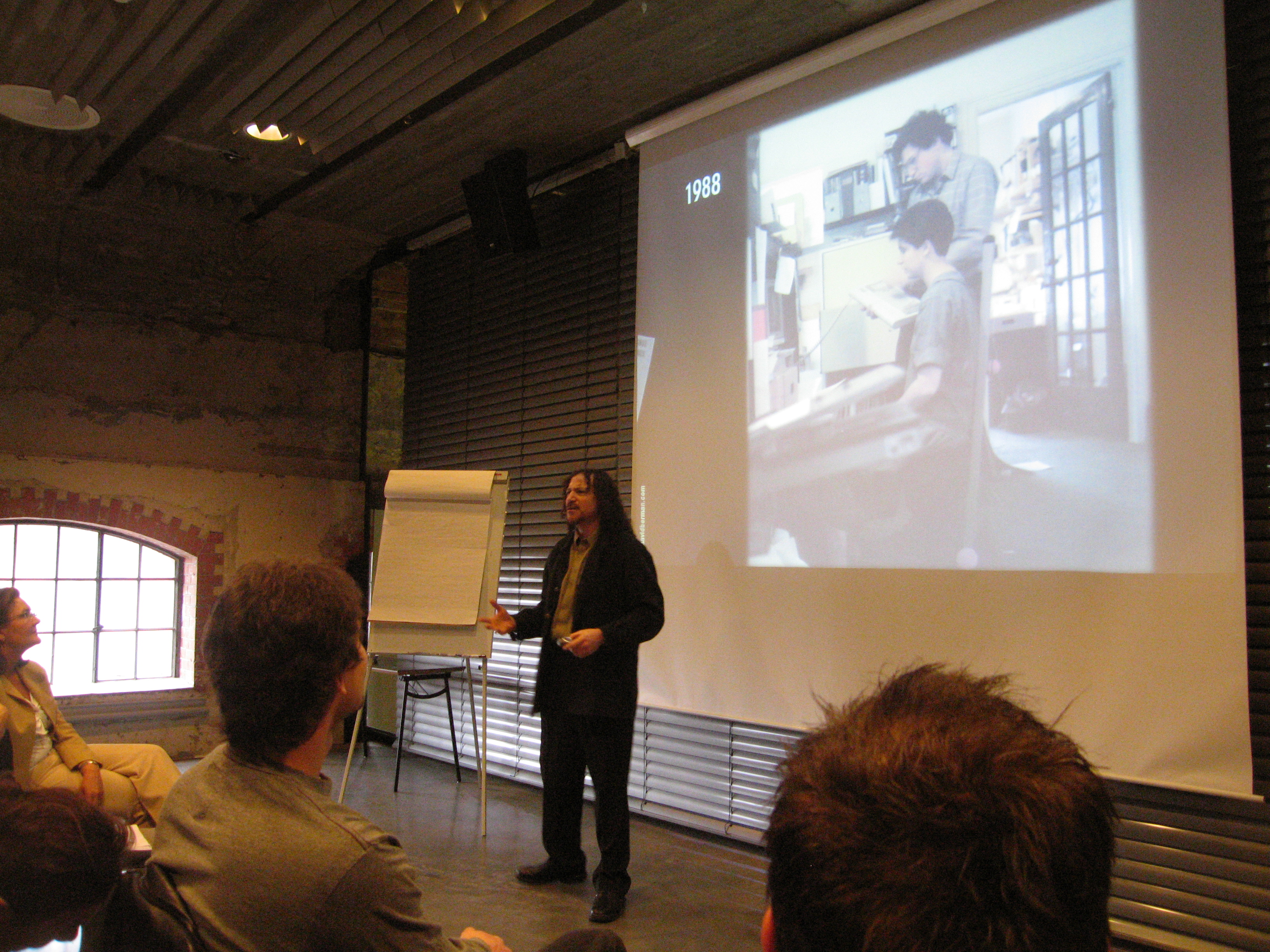 Photo of David Berman standing in front of an audience, presenting slides.