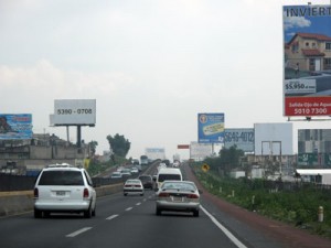 Photo of a road in Mexico crowded with billboards.